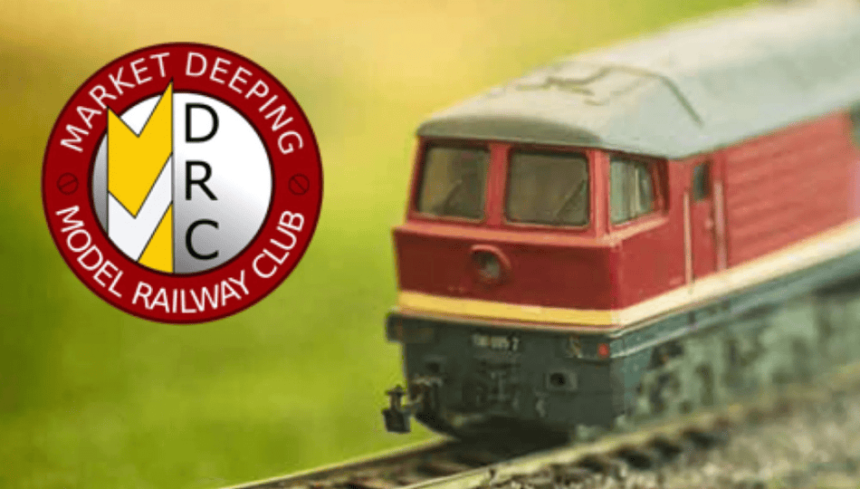 Enthusiasts exploring detailed model train displays at the Stamford Model Railway Show, featuring intricate miniature landscapes, trains, and tracks in a bustling event setting.